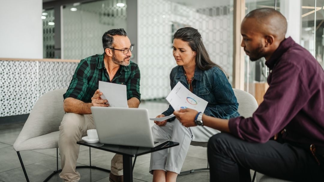 Business professionals sitting around a laptop