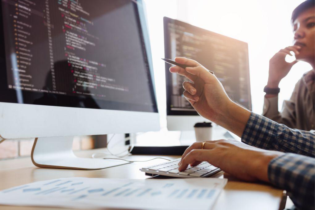 Person pointing to a computer screen with a pencil