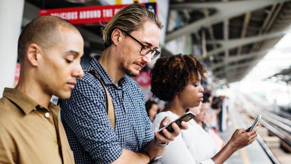 Grupo de três pessoas olhando para seus telefones